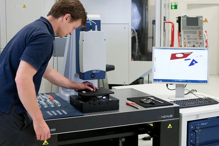 Technician operating a Polytec Nexus 3D measurement system, analyzing parts with precision metrology software displayed on screen.