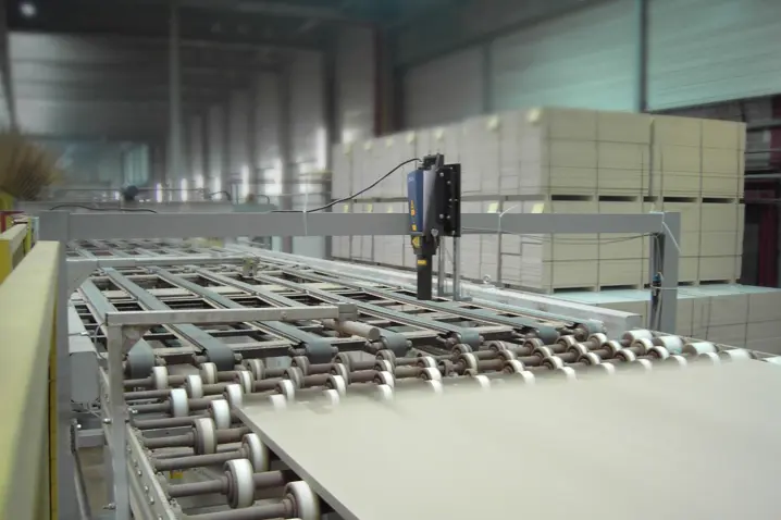 Automated industrial cutting system processing large flat panels with precise laser speed and length control in warehouse.